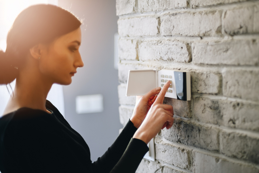 Woman entering security pin on home alarm keypad.